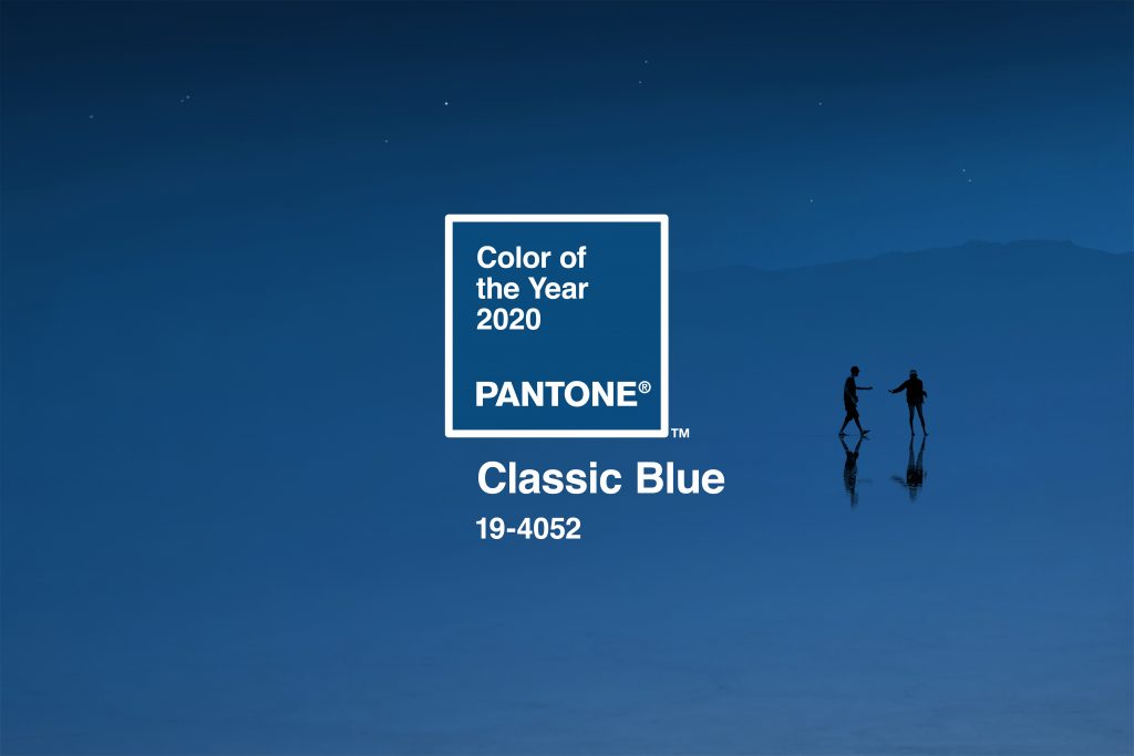 "Color of the Year 2020, Pantone, Classic Blue 19-4052" Two silhouetted individuals reaching towards each other in front of a rich, dusk blue.